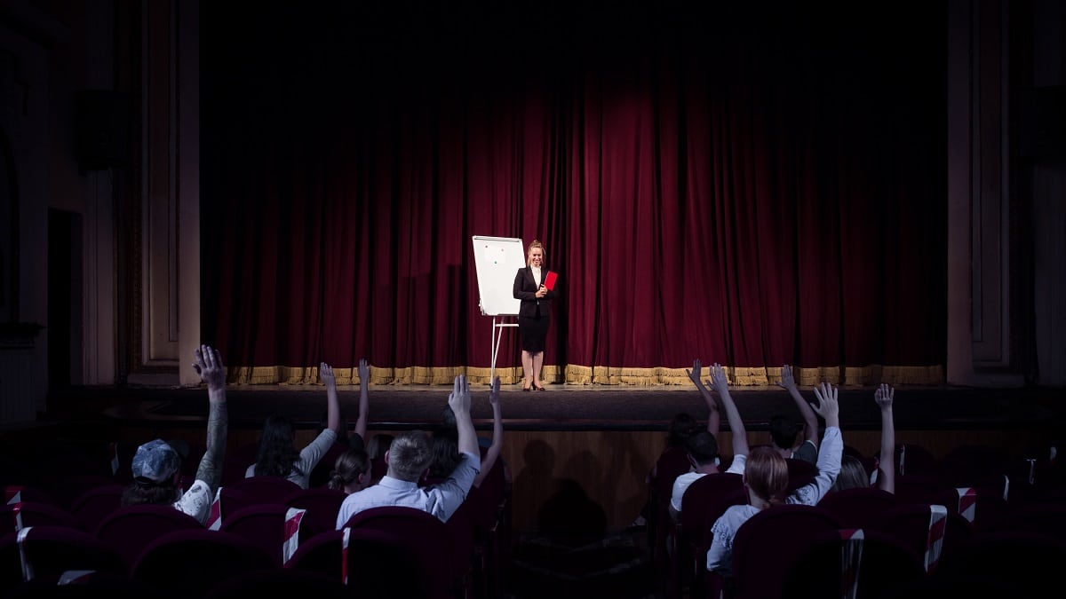 female speaker giving presentation in hall at Symposium